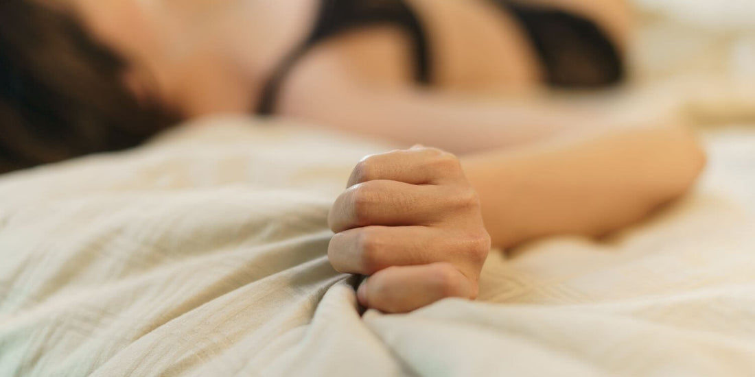 Mujer en la cama sintiendo un orgasmo con un succionador de clítoris