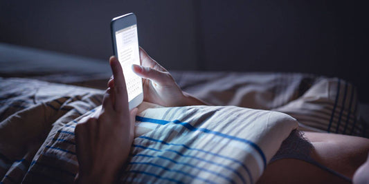 Mujer en la cama con el móvil en la mano; guía de sexo a distancia en pareja